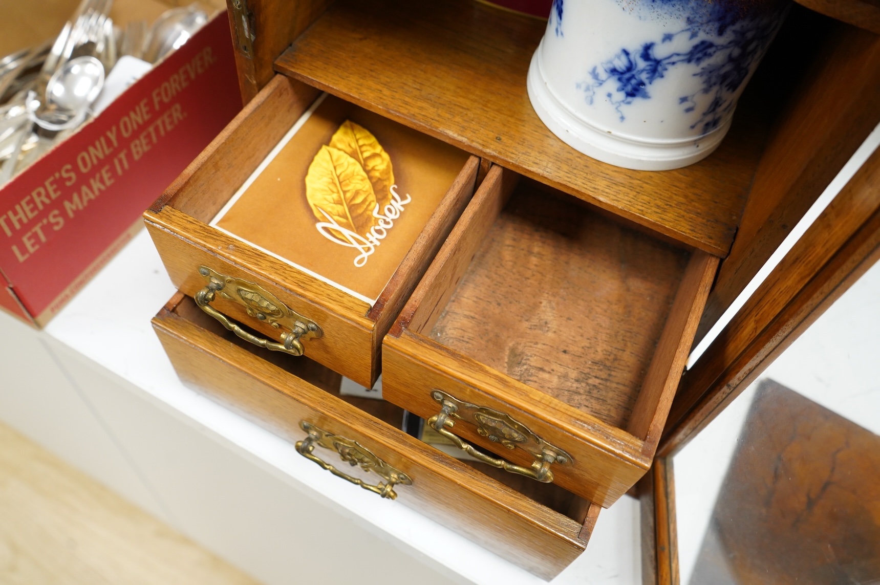 An Edwardian oak smoker's cabinet, with Doric blue and white tobacco jar and cover, 38cm high x 29.5cm wide.
